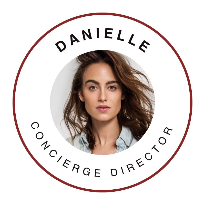A circular badge with a photo of a woman with long brown hair, a light blue shirt, and a neutral expression. Around the photo, the text reads "DANIELLE" at the top and "CONCIERGE DIRECTOR" at the bottom, all within a thin red border.