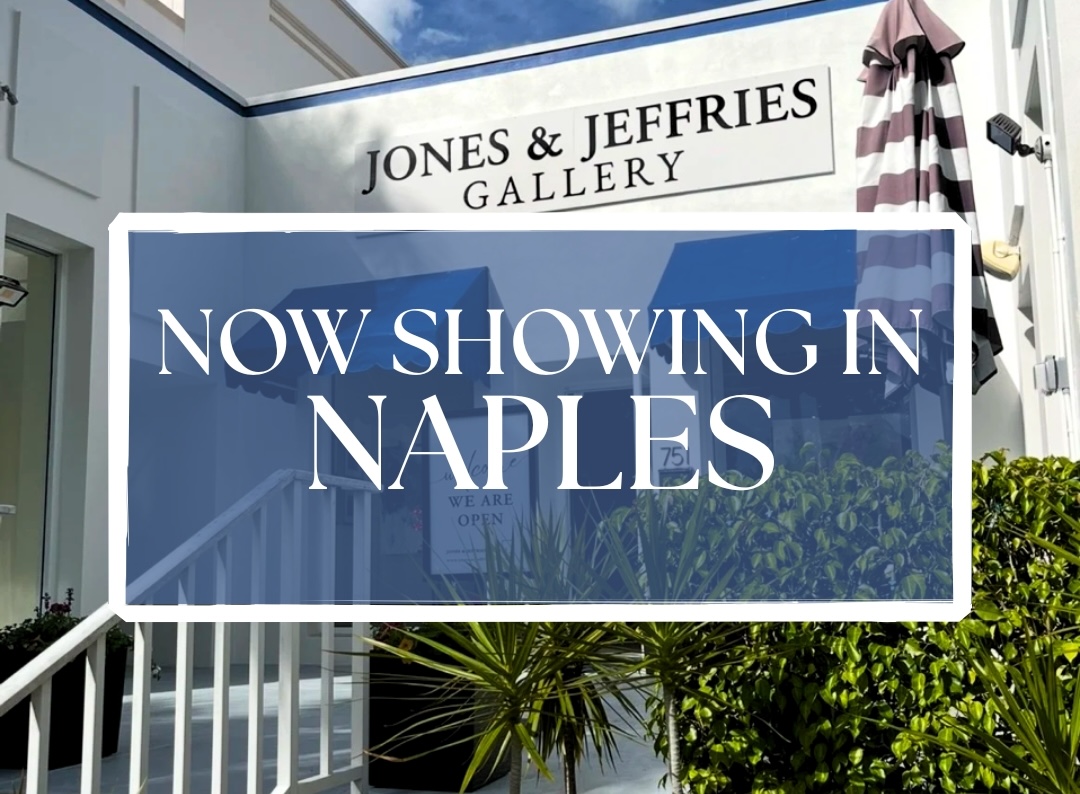 A sign in front of a white building reads “Jones & Jeffries Gallery.” Overlaid text in a blue box says, “Now showing in Naples.” The scene includes a staircase, plants, a striped umbrella, and a partly cloudy sky above.