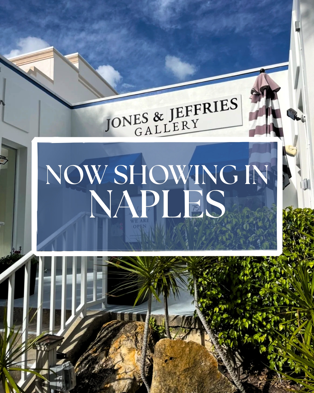 A white building with a sign reading "Jones & Jeffries Gallery." In front, a blue overlay reads "Now Showing in Naples." There are tropical plants, rocks, a striped umbrella, and a partly cloudy sky in the background.